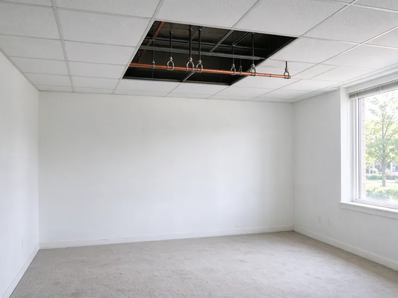 A new copper branch line on hangers above a suspended ceiling with two tiles removed